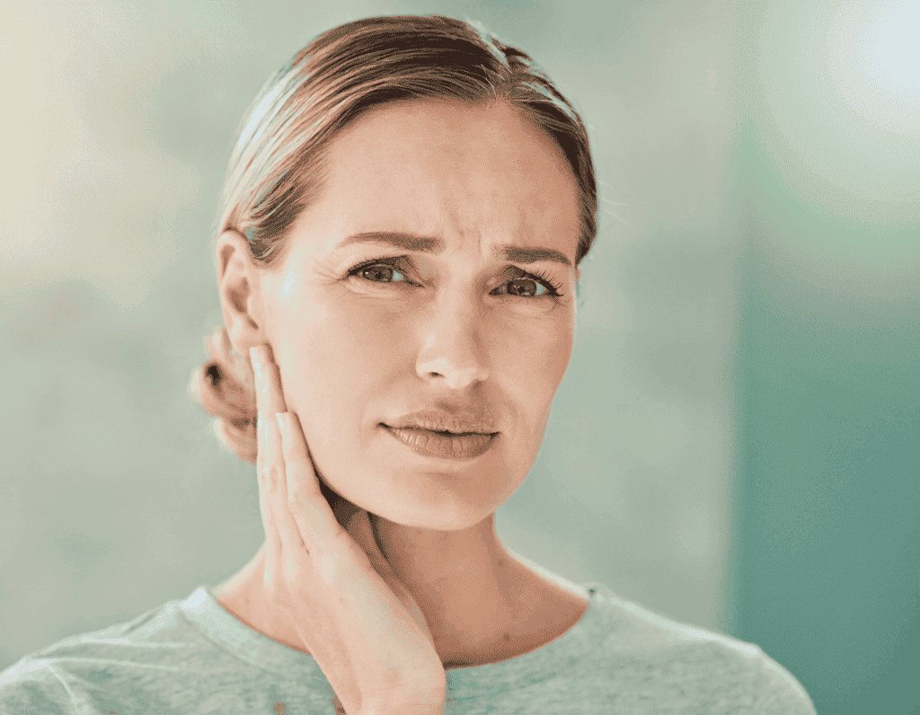 Woman touches her painful jaw near the ear – TMD symptoms in women, JUST KFO Cologne